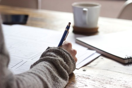 "Student's hands writing answers on an 11+ comprehension test paper with pencil and eraser nearby"